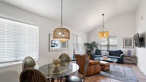 Un salon spacieux avec une table à manger en verre, un canapé en cuir et un grand tapis.
