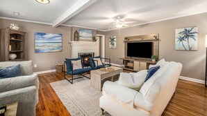 A living room with a fireplace, a TV, and a ceiling fan. - Spacious 4br/3ba Park Circle Home. Great Location! (North Charleston)