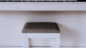 Un piano blanco con un banquillo al frente.