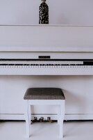 Un piano blanco con un banquillo al frente.