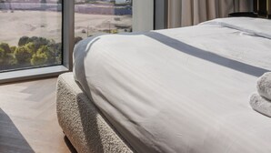 A hotel room with a large window offering a city skyline view.