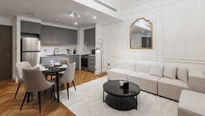 A modern kitchen with grey cabinets, a dining table with chairs, and a black coffee table.