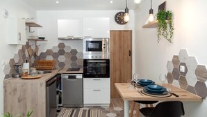 Een moderne keuken met witte kasten, een inbouwoven en een eethoek met een houten tafel en stoelen.