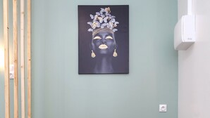 Een woonkamer met een grijze bank, een zwarte bijzettafel met een kaars, en een wandkunstwerk.