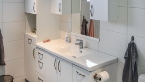 Un bagno moderno con lavandino bianco, uno specchio e un portascopevoli.