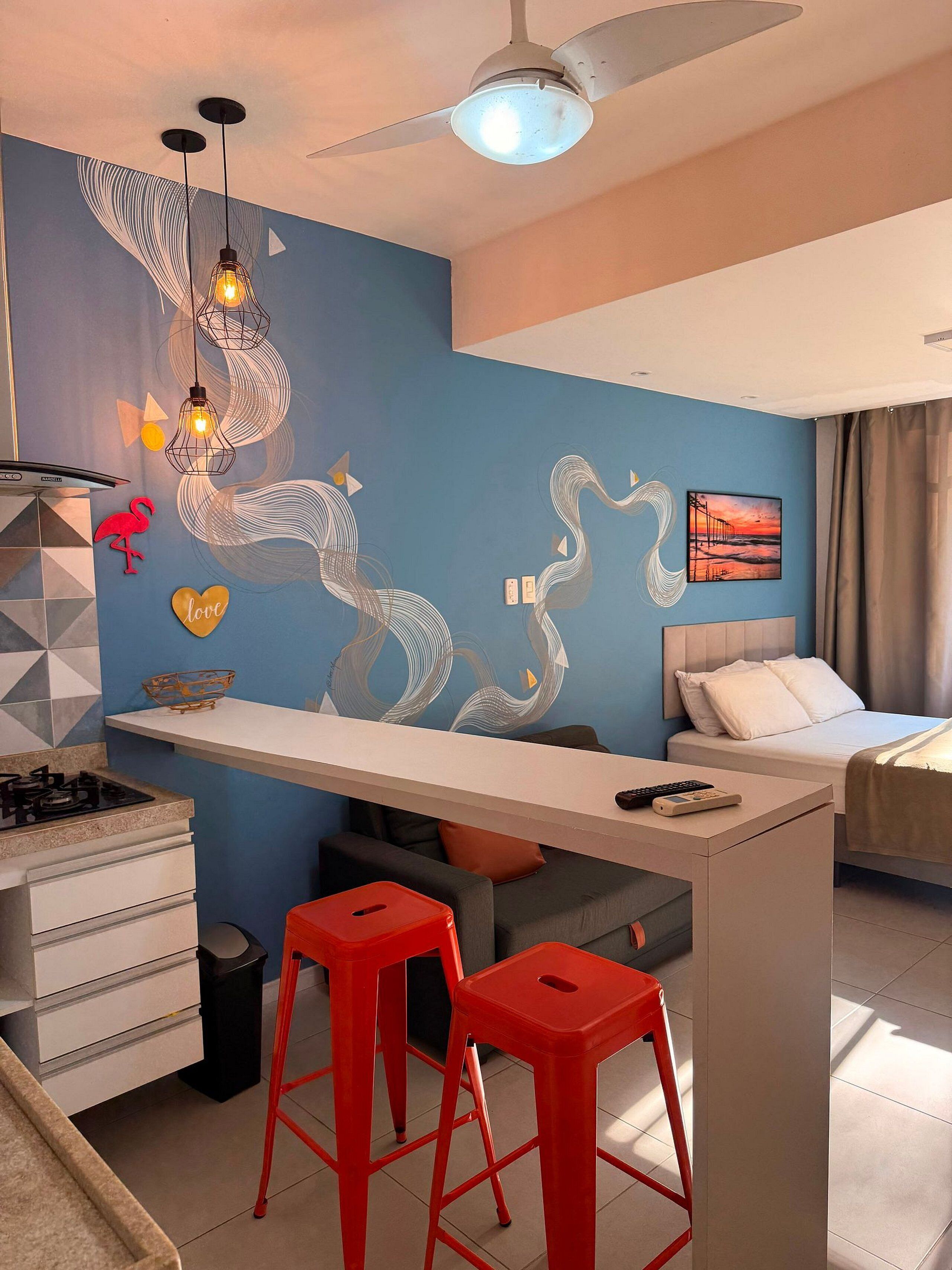 A modern hotel room with a kitchen area, a dining table, and a bed.