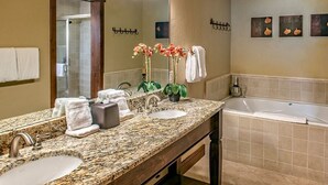 Un baño con encimera de granito, dos lavabos, un espejo grande, una ducha y una bañera.