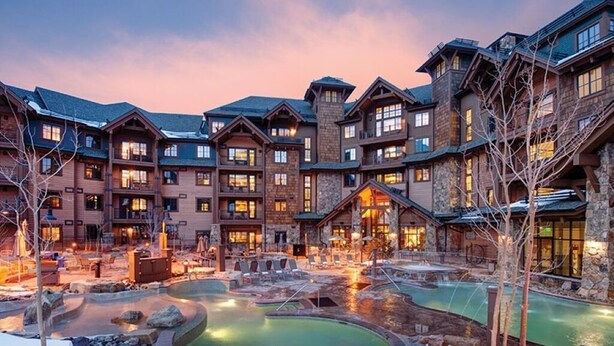 Un complejo de lodges con varias construcciones, piscina al aire libre climatizada y terreno cubierto de nieve.