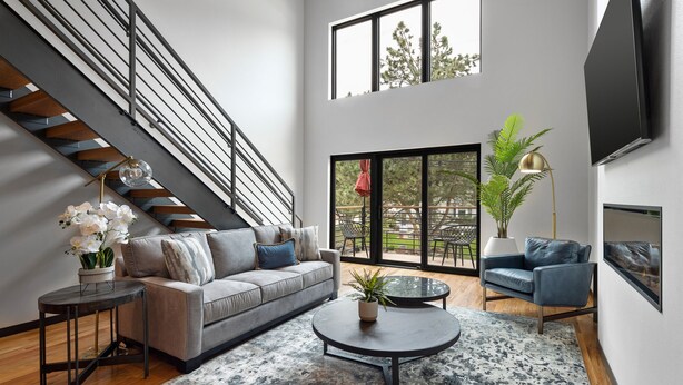 Ein modernes Wohnzimmer mit grauem Sofa, Couchtisch und Treppe.