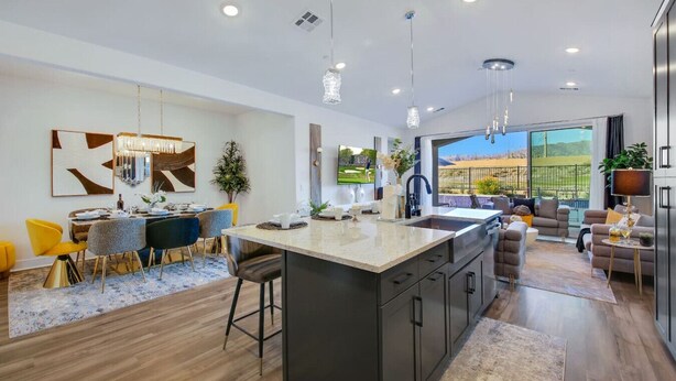 A modern kitchen with a central island, pendant lighting, and a view to an outdoor patio. - New Large Home-Views-Mountain, Lake & Golf (Indio)