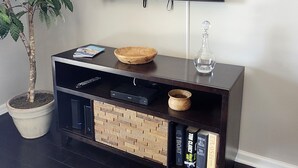 Un mueble moderno de entretenimiento con un televisor de pantalla plana, una planta en maceta y una mesita de madera.