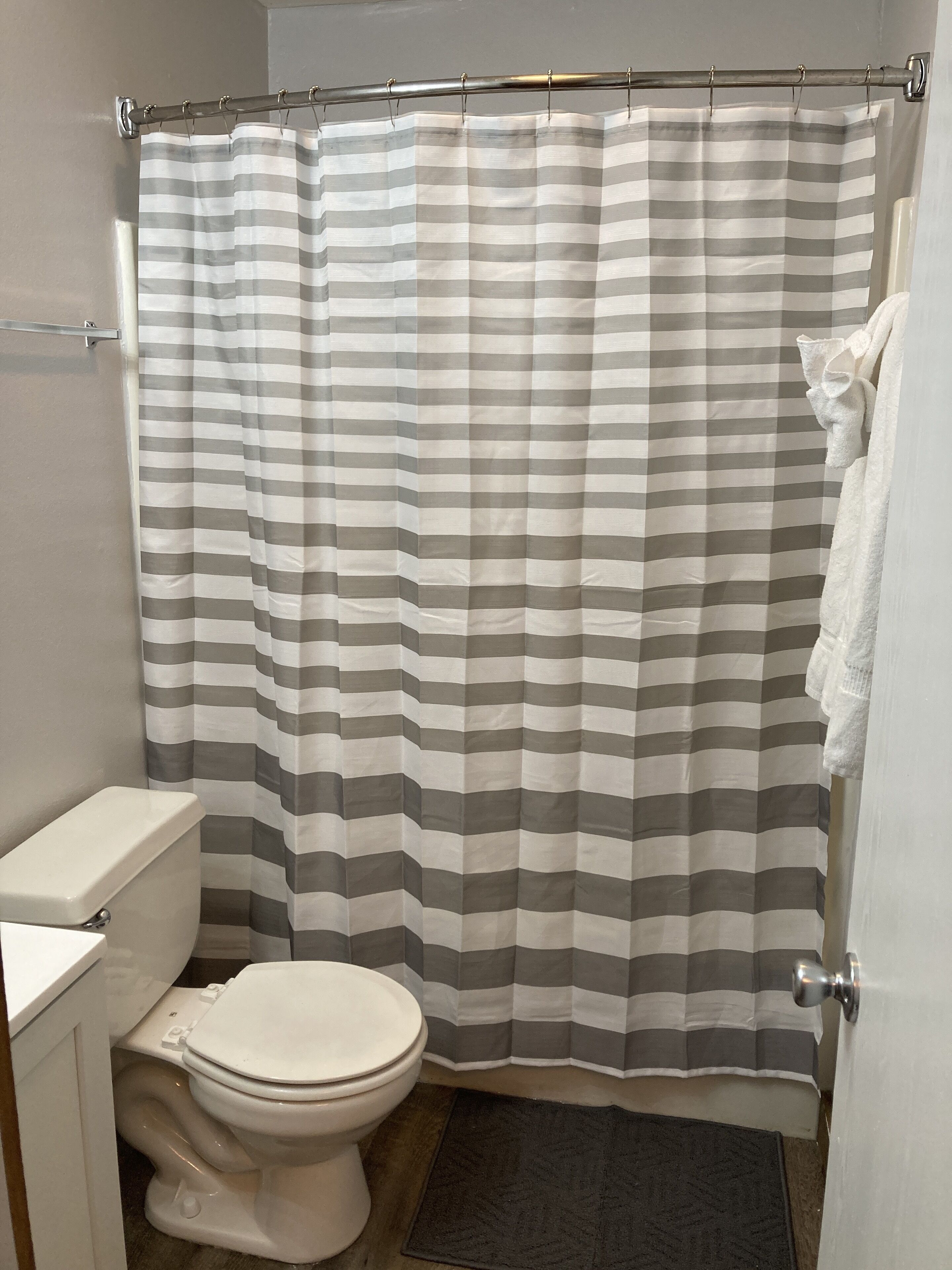 A bathroom with a striped shower curtain, a toilet, and a towel rack.