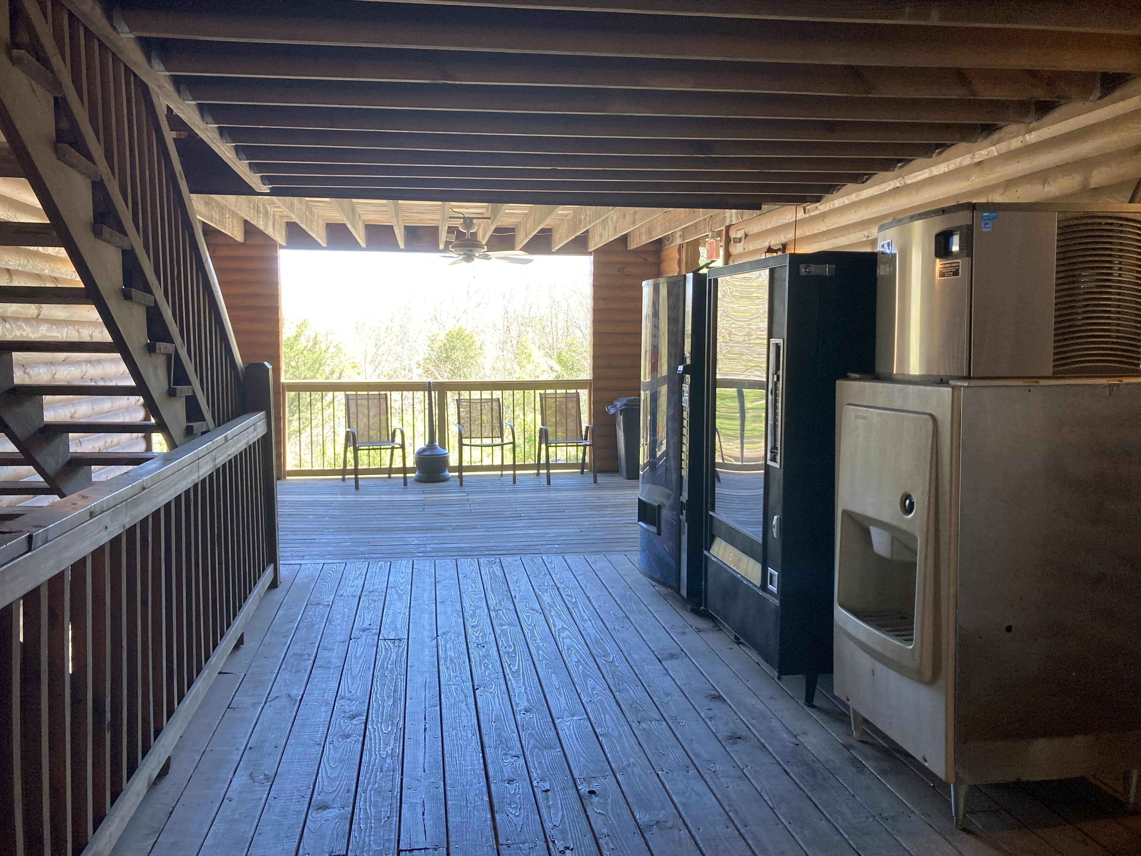 A wooden deck with a staircase, outdoor seating, and a refrigerator.