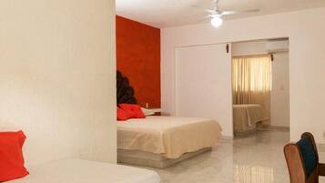 Una habitación de hotel con dos camas, un ventilador de techo y un baño con ducha.