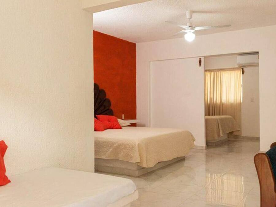 Una habitación de hotel con dos camas, un ventilador de techo y un baño con ducha.