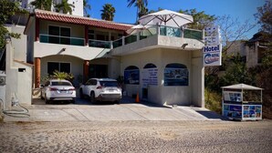 Um hotel com estrutura em dois andares, área externa coberta e uma placa indicando ser um hotel Royal Pacifics.