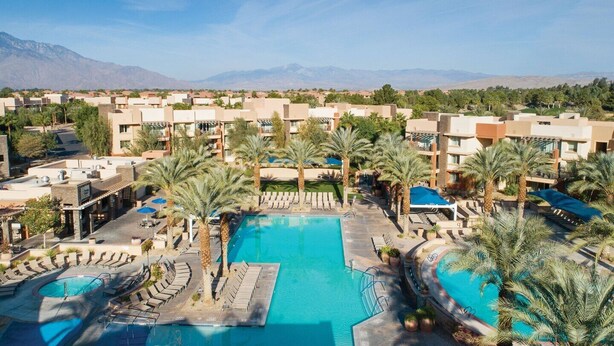 Ein Resort mit mehreren Schwimmbecken, Palmen und einer Bergkulisse im Hintergrund.