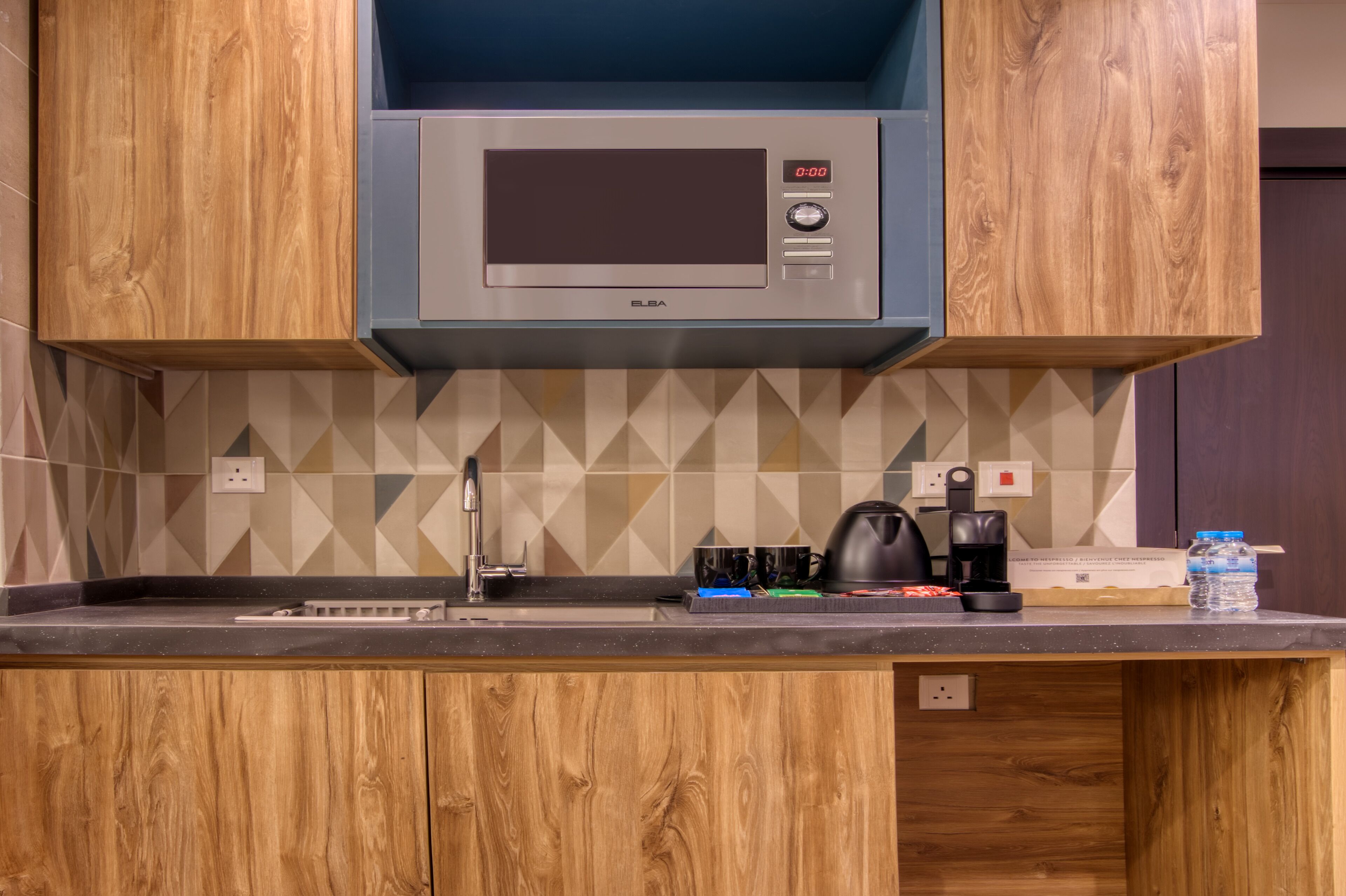 A kitchen with a built-in microwave, a coffee maker, and a water bottle on the counter.