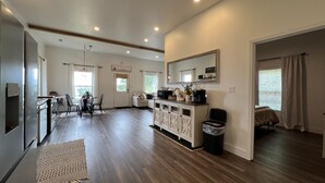 Una cocina amplia con suelo de madera, un comedor con sillas, un sofá y una zona de café.