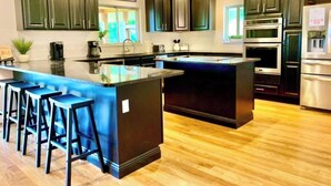 A modern kitchen with dark cabinets, a central island with bar stools, and built-in appliances.