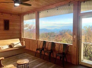 Una cabaña de madera con balcón, cama y vistas a un paisaje montañoso.