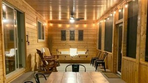 A wooden-paneled room with a large dining table, chairs, and a bench.
