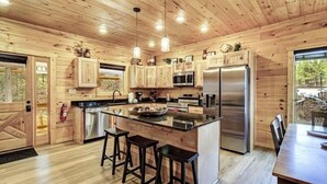 A modern kitchen with wooden cabinetry, stainless steel appliances, and a central island with bar stools.
