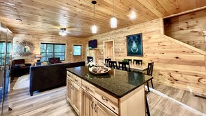 A cabin interior with a wooden interior, a dining area, and a kitchen with a central island.
