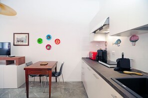 Une cuisine compacte comprenant une table à manger, des chaises, un téléviseur et un four à micro-ondes.