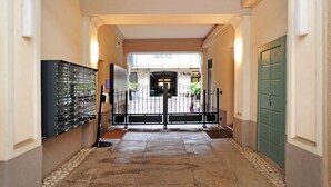 Un pasillo con una verja, una puerta verde y un edificio al fondo.
