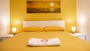 A hotel room with a bed, two bedside lamps, a painting on the wall, and a towel on the bed. - Sun&Moon Apartment (Bari)