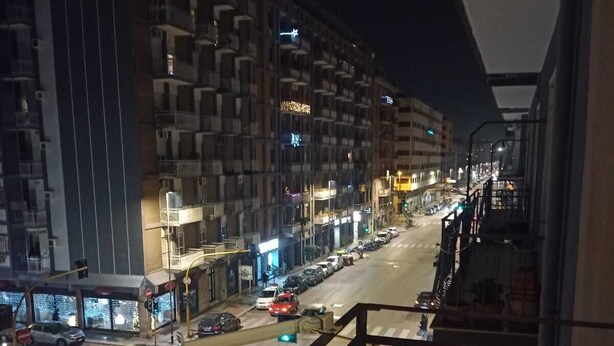 A nighttime view of a city street from a balcony with a railing. - Sun&Moon Apartment (Bari)