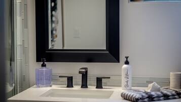 A bathroom with a white sink, black faucet, and a mirror with a black frame.