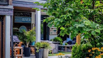 An outdoor seating area with wicker furniture, potted plants, and a sign reading "welcome to the RIVER".