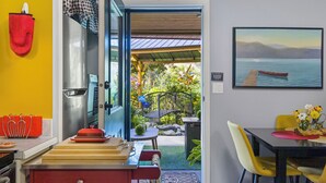 Un comedor con una mesa, sillas y vistas a un jardín a través de una puerta abierta.