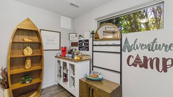 Eine gemütliche Küche mit einem Holzbottenschrank, einer Kaffeestation und einer Wand mit Dekoration zum Thema 'Adventure Camp'.