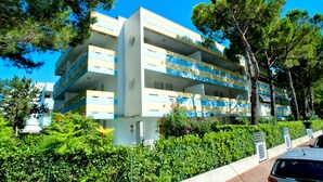 A multi-story building with balconies, surrounded by greenery and trees. - Enjoy Your Stay in our Cozy Bright Flat (San Michele al Tagliamento)
