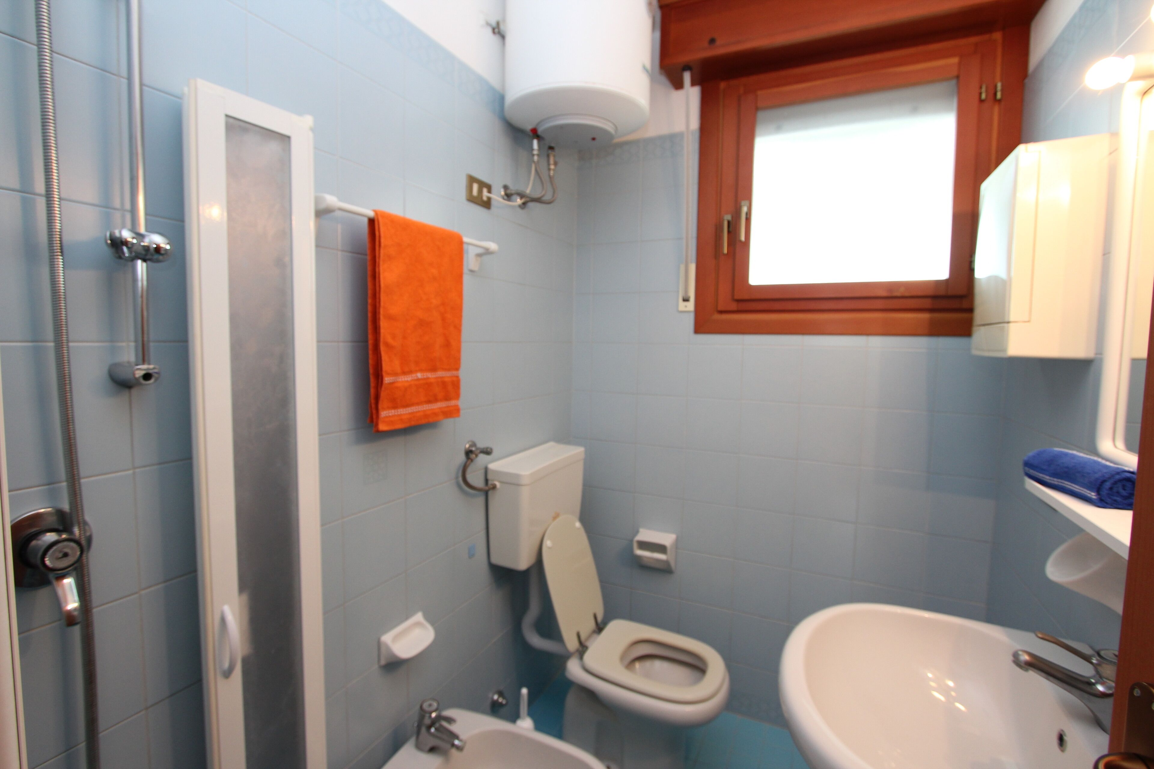 Ein Badezimmer mit Dusche, Toilette, Waschbecken und einem Fenster über dem Waschbecken.