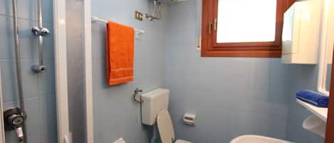 Ein Badezimmer mit Dusche, Toilette, Waschbecken und einem Fenster über dem Waschbecken.