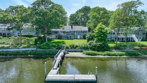 A waterfront property with a dock leading to a house with a balcony and a flagpole. - Waterfront, Incredible Views and Private Dock! (Yarmouth)
