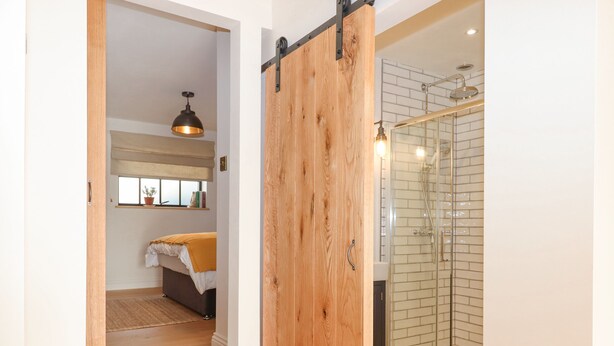 Une salle de bain moderne dotée d’une douche à parois de verre et d’une porte en bois.
