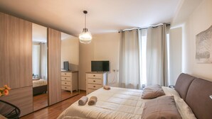A bedroom with a bed, a TV, a mirror, and a window with curtains. - 3 bedroom nice apartment in Rovereto (Rovereto)