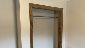 Una habitación con un armario de madera, una mesita y suelo de tono claro.