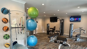 Une salle de sport équipée de matériel d’exercice, d’un téléviseur et d’un tapis à motifs.