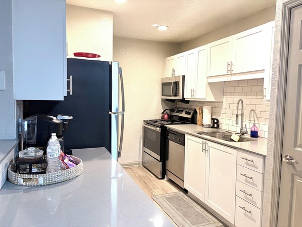 A compact kitchen with a refrigerator, microwave, stove, and sink.