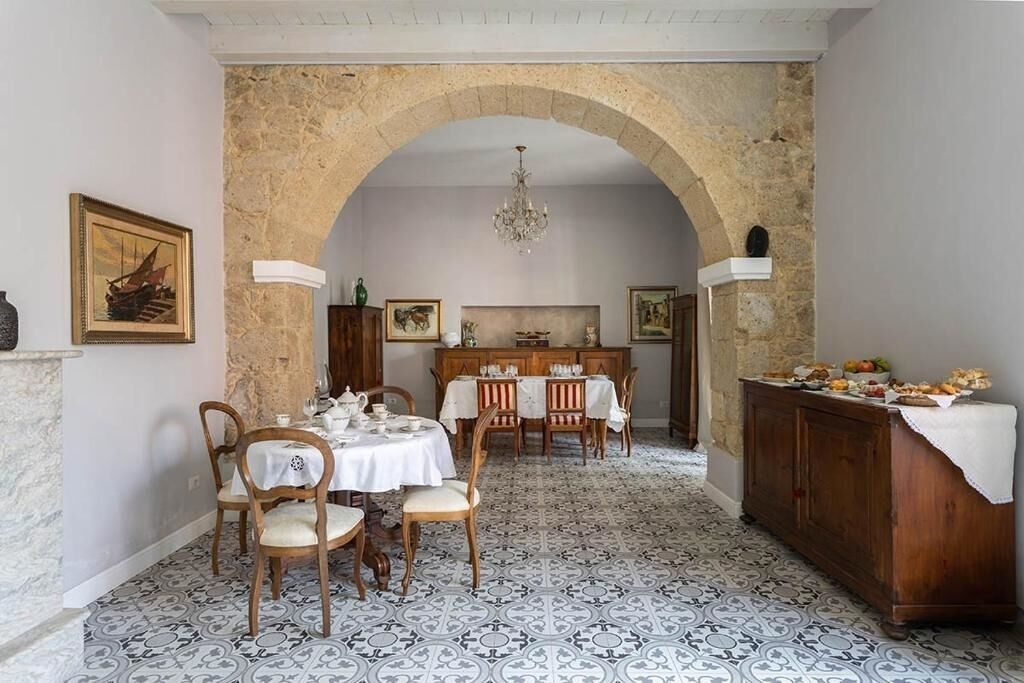 A dining area with a stone archway, a chandelier, and a buffet table.