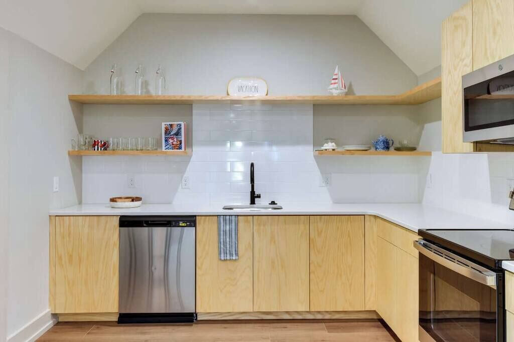 Eine moderne Küche mit Holzschränken, einer weißen Arbeitsplatte, einem Geschirrspüler und einem Einbauofen.