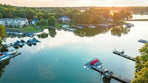 A marina with boats docked, a dock with a covered area, and buildings in the background. - Spacious Lakefront Retreat, Enjoy Dock and Pool (Mooresville)