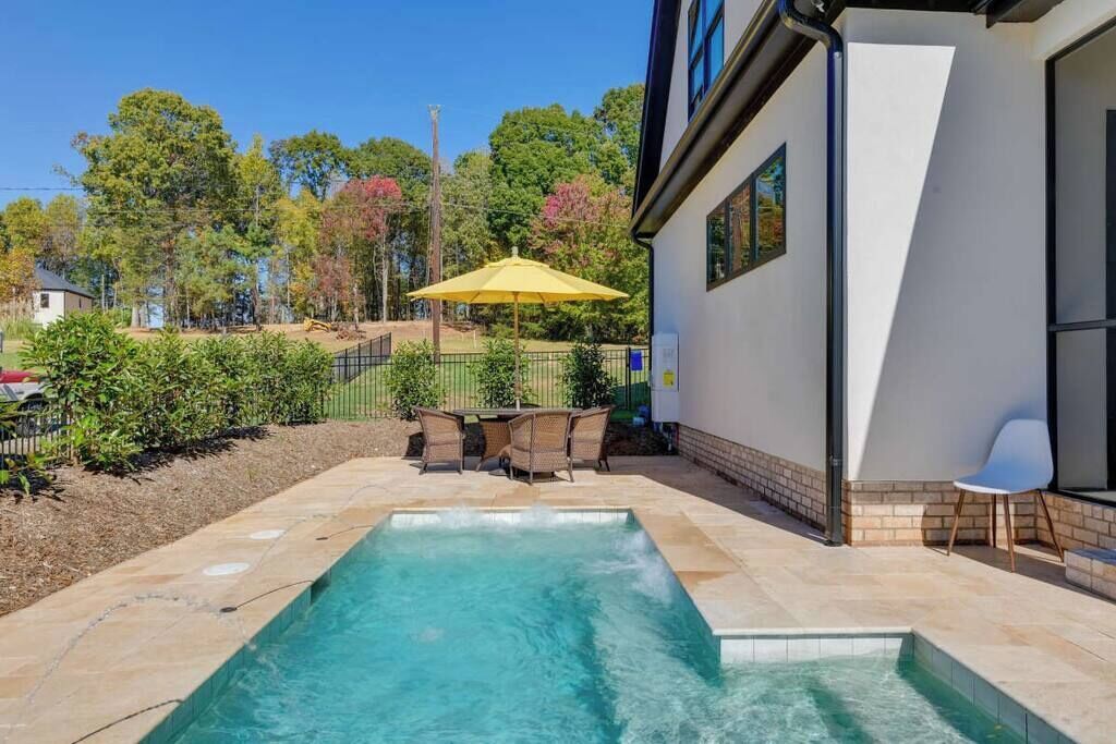 Ein Schwimmbecken mit Tisch und Stühlen, umgeben von einem eingezäunten Garten.