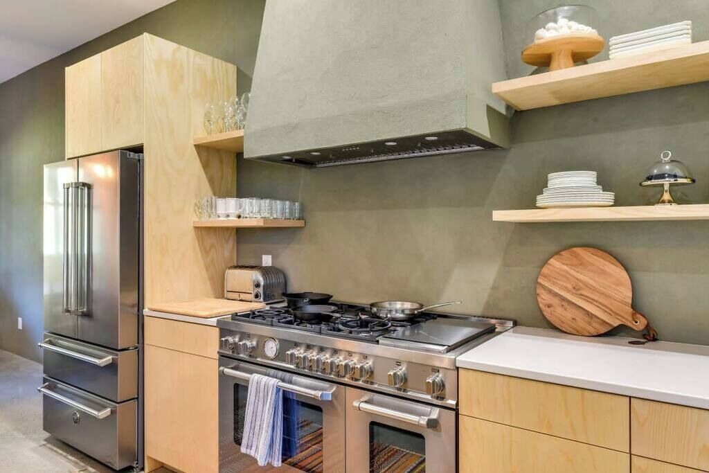 A modern kitchen with stainless steel appliances, wooden cabinets, and a built-in oven.